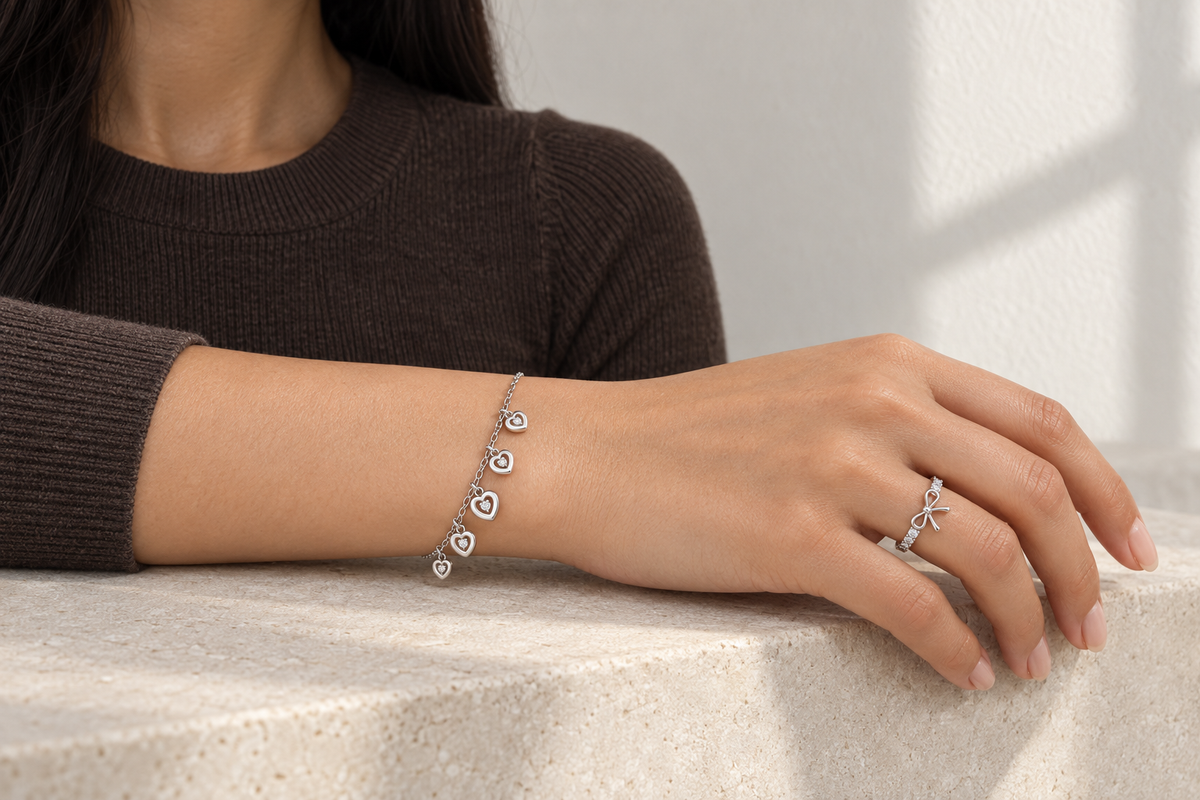 Wrist wearing the Heart Fringe Bracelet and the Fine Bow Ring in white gold