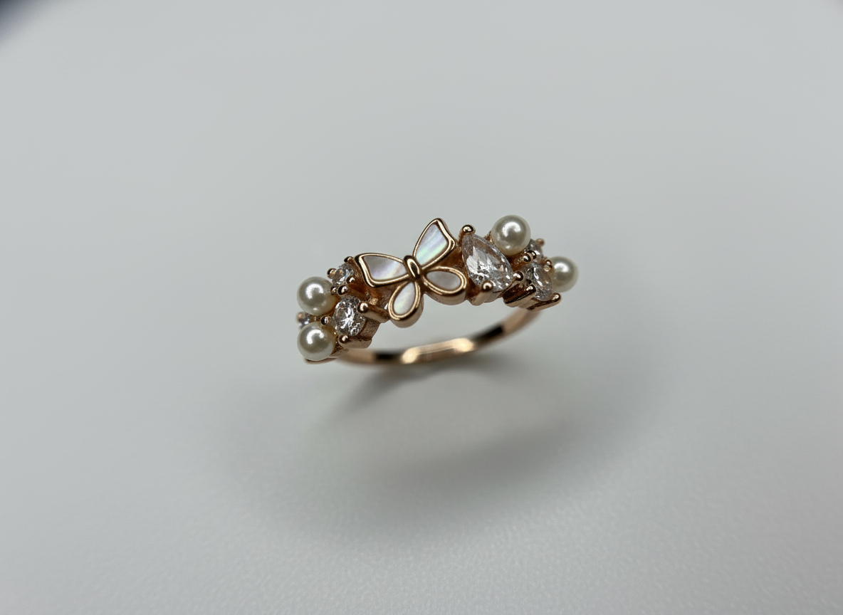Angled view of the unique butterfly fashion ring catching studio light to emphasize the gleam of the pearls and high-polish gold.